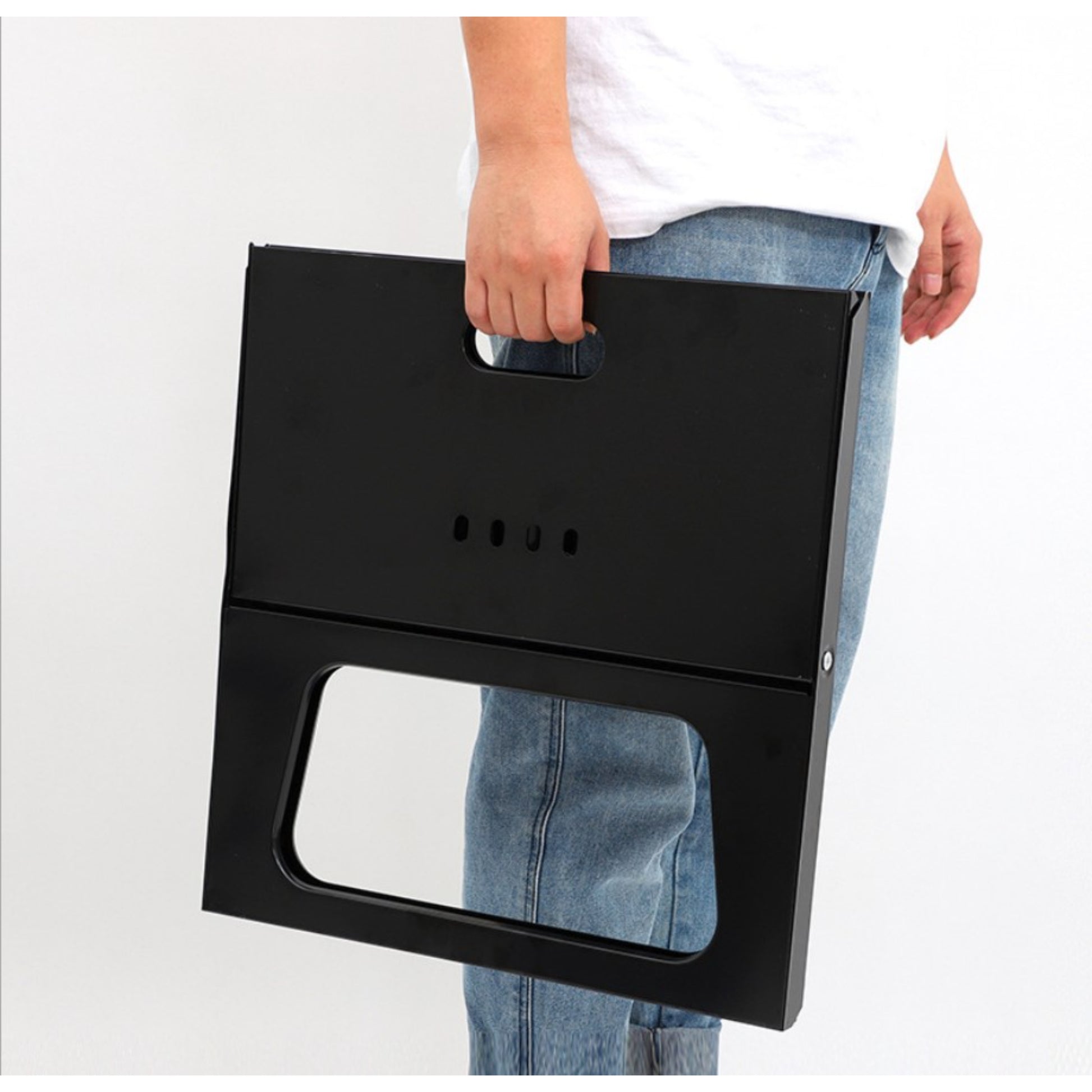 Person holding a black folding stool against a white background