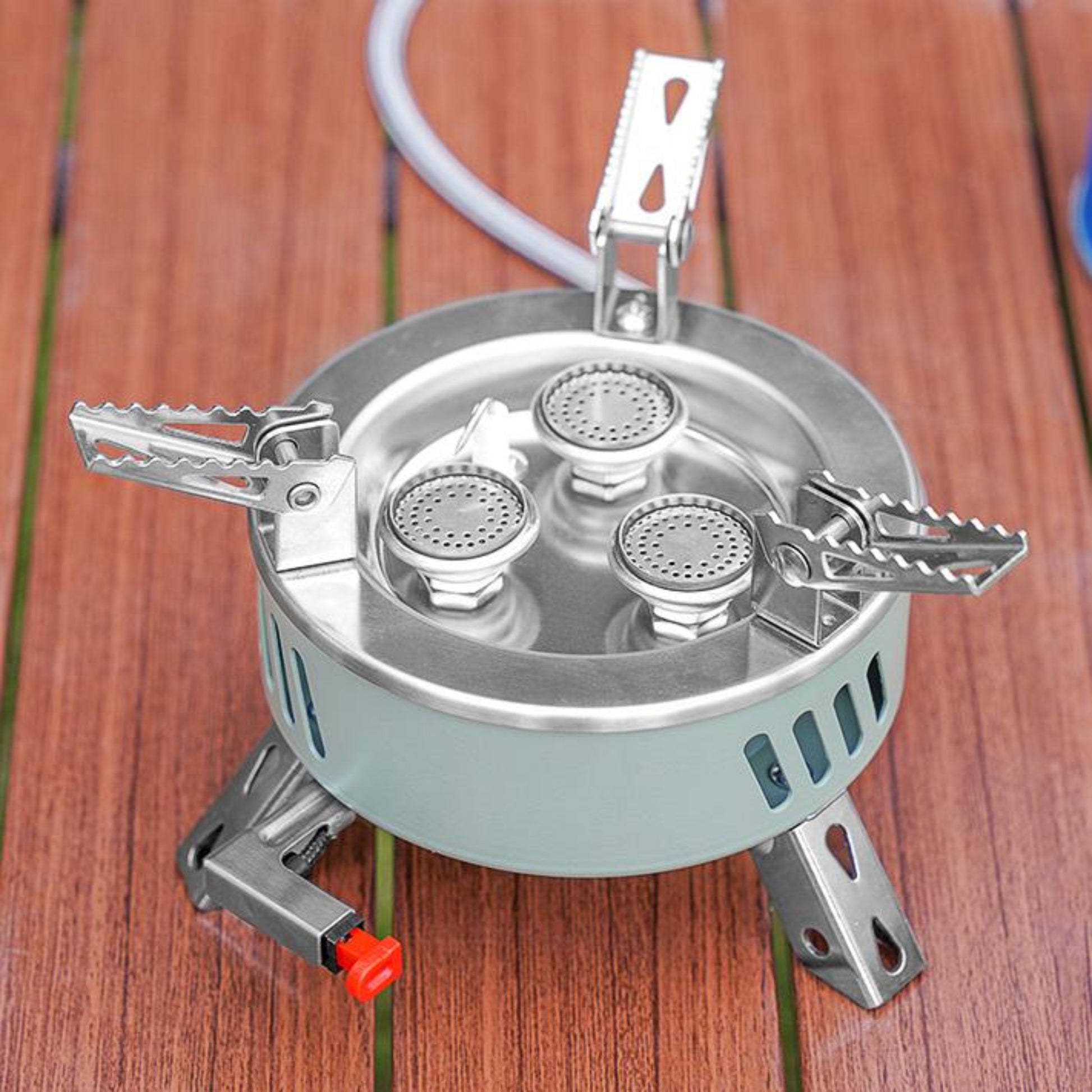 Close up of STARCAMP round camping stove red piezo ignition button and brass gas valve connector