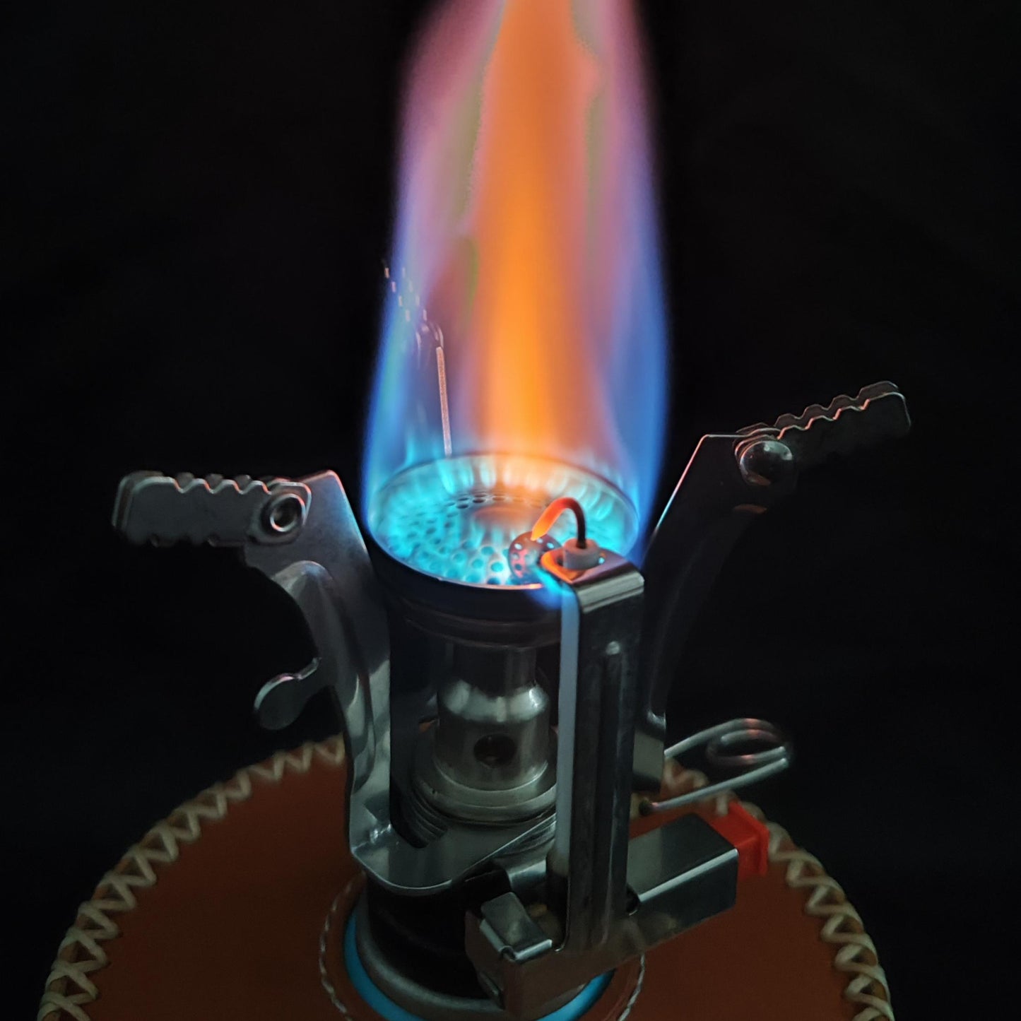 Close-up of a lit butane lighter with a visible flame against a dark background