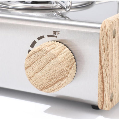 Close-up of a portable stove with wooden handle and control knob.