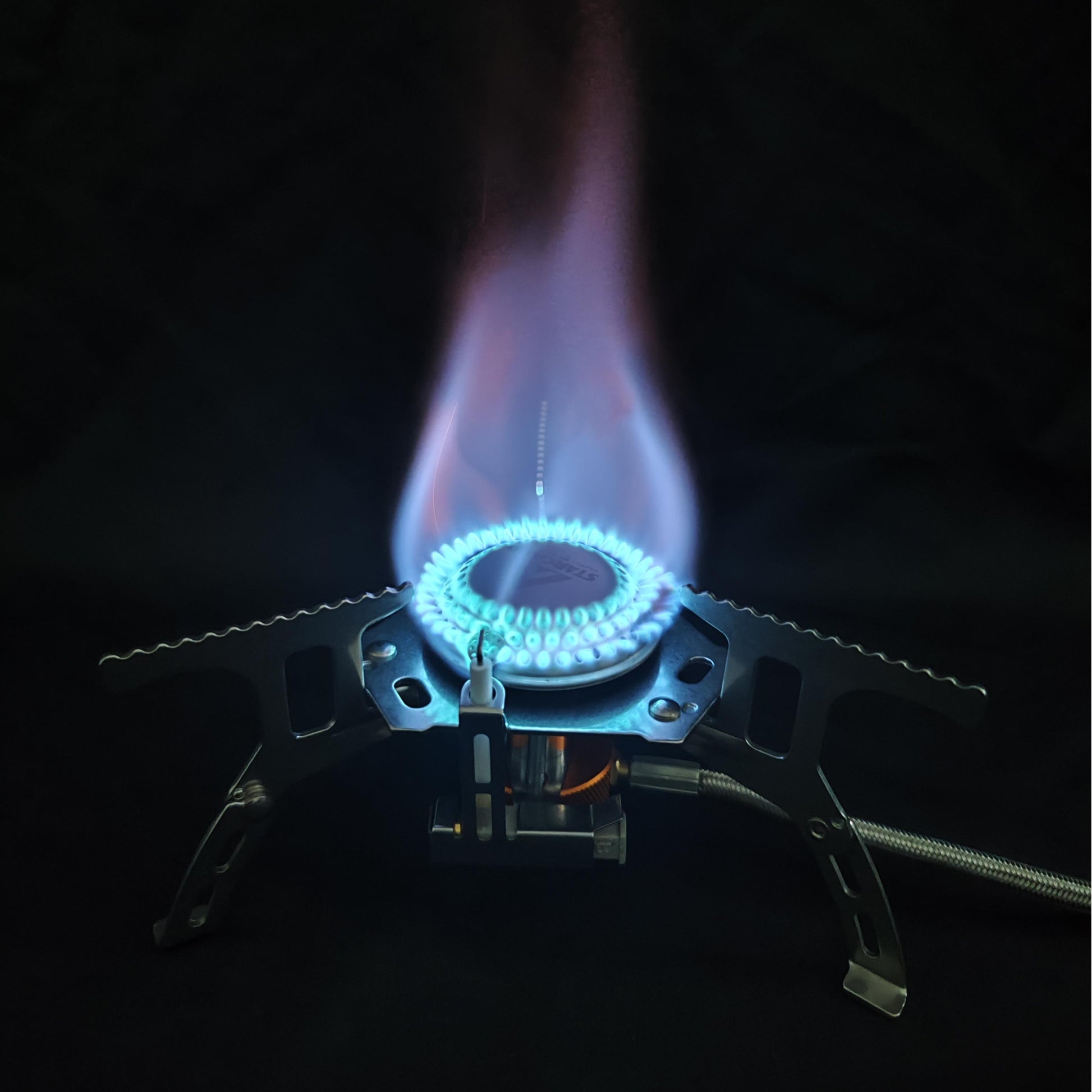 Close-up of a gas stove burner with flames on a black background